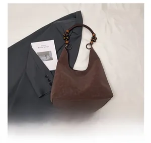 Détail du sac cabas en daim marron foncé avec poignées en perles de bois vintage