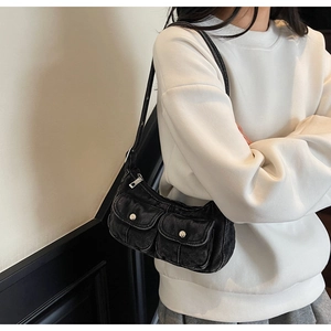 Detail of vintage Y2K black denim shoulder bag with decorative front pockets and metal buttons