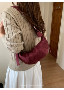 Detail of burgundy faux suede dumpling bag showing its unique pleated texture and wide strap
