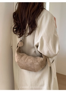 Detailed view of the khaki suede croissant bag with minimalist stitched panels on a model