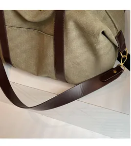 Close-up of military green canvas tote bag with brown leather strap and gold metal hardware