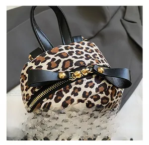 Detail of leopard print backpack featuring gold metal zipper and leather bow decoration