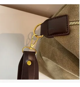 Detail of green canvas tote showing premium gold-plated hardware and brown leather trim