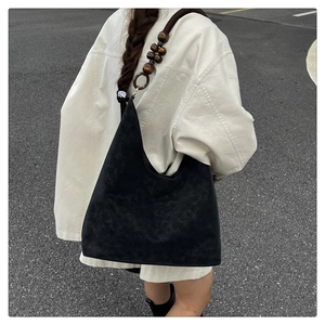 Detail of hobo bag featuring dark wooden bead accents and matte black suede texture