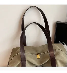 Detail of durable leather handles and golden zippers on an olive canvas tote bag