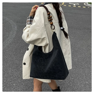 Détail d'un grand sac cabas en daim noir avec bandoulière rétro en perles de bois et métal