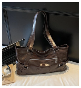 Close-up of a vintage brown tote bag showing high-gloss leather and metal zipper pocket