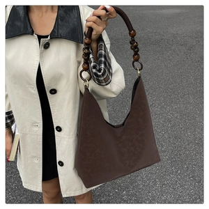 Détail du sac fourre-tout en cuir marron foncé avec bandoulière rétro en perles de bois