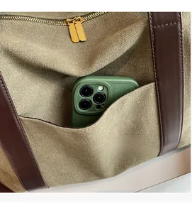 Close-up of olive green canvas tote with leather pocket and smooth metal zippers