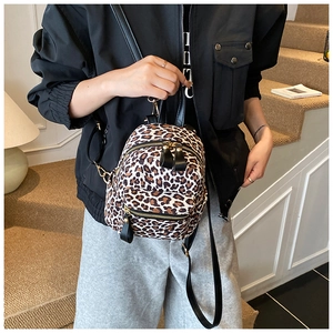 Detailed view of the mini leopard print backpack worn by a model on a staircase