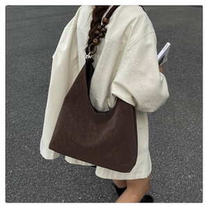 Große braune Hobo-Tasche mit dekorativen dunklen Holzperlen am Trageriemen im Detail