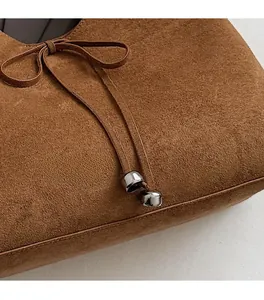 Detail of brown matte suede bag featuring leather bow knots and silver metal hardware