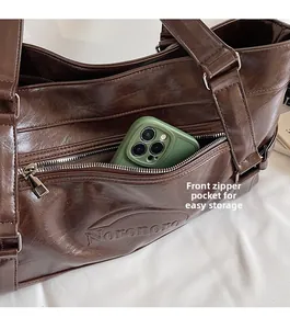 Detail of dark brown leather tote featuring a front zipper pocket for easy phone storage