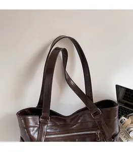 Detail of dark brown leather tote bag showing glossy texture and silver buckle straps