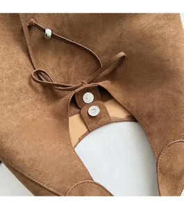 Detail of brown suede handbag featuring a secure magnetic closure and decorative bead