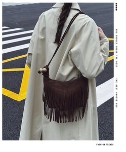 Detail of dark brown suede tassel shoulder bag with wooden beads on a stylish model