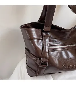 Close-up of deep brown textured leather tote bag showing Noron logo and stitching