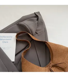 Detail of suede shoulder bag featuring a decorative drawstring bow and textured finish