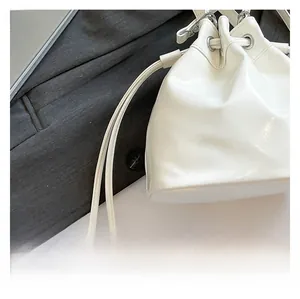 Detail of white glossy bucket bag showing fine leather texture and drawstring closure