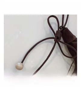 Close-up of brown suede drawstring details with elegant off-white decorative beads