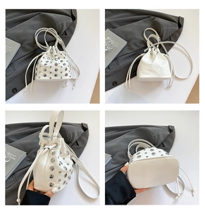 Detail of white bucket bag featuring silver studs and adjustable shoulder strap