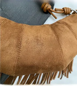 Close-up of brown suede crescent bag featuring fringe details and precision stitching