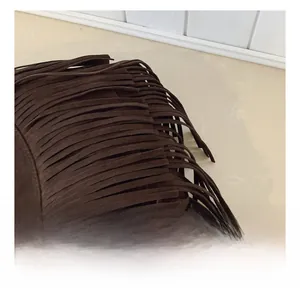 Detail showing long suede fringe on dark brown crossbody bag with refined texture