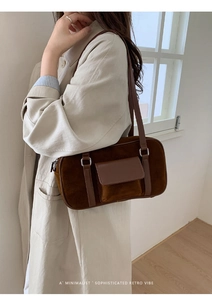 Close-up of minimalist brown suede underarm bag with retro flap pocket and slim strap