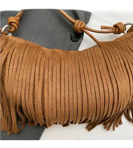 Close-up of brown suede tassel bag detailing with long fringe and knotted strap