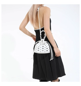 White leather bucket bag with silver studs on model in black dress, fashion side view