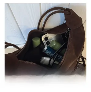 Internal capacity of brown suede tassel shoulder bag with daily items inside