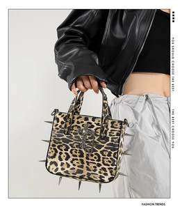 Close-up of leopard print tote bag with silver spikes, metal cross and chain details