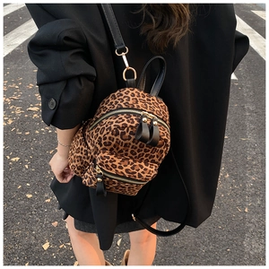Detail of trendy leopard print mini backpack with golden zippers and black leather straps