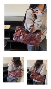 Close-up of vintage burgundy wax leather tote bag with decorative buckles and zip pocket