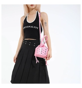 Close-up of pink patent leather bucket bag with silver studs and drawstring closure