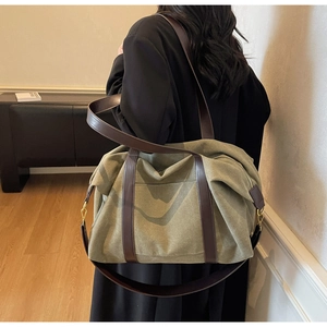 Detail view of large olive green canvas tote bag with brown leather handles and gold hardware
