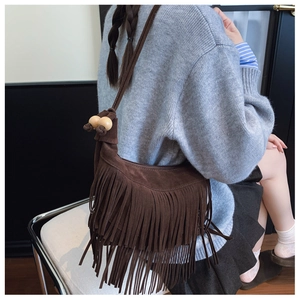 Detail of dark brown suede tassel shoulder bag with wooden bead accents and zipper closure