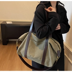 Detail of army green canvas tote bag with brown leather straps and gold metal hardware