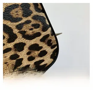 Macro shot of leopard print fabric texture with black edge piping on a stylish tote bag