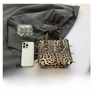 Detail of leopard print bag with silver rivets, metal cross pendant and chain strap