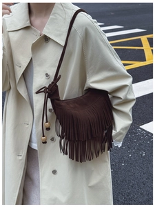 Detail of dark brown suede crossbody bag with long fringes and wooden beads