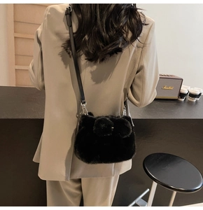 Detail of black plush crossbody bag with animal ears on a gray blazer suit