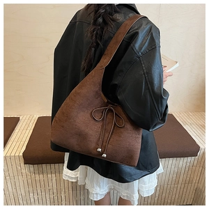 Detailed view of brown matte suede tote bag with ribbon bow worn on the shoulder
