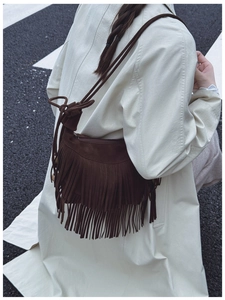 Détail du sac bandoulière en daim marron foncé avec de longues franges de style bohème
