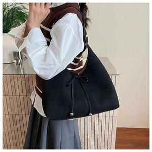 Detail of black suede hobo bag with bow drawstring and silver metal ball accents