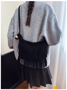 Détail d'un sac bandoulière en daim noir avec franges et perles en bois sur un modèle