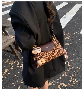 Detail of leopard print crossbody bag with teddy bear charm in a street style setting