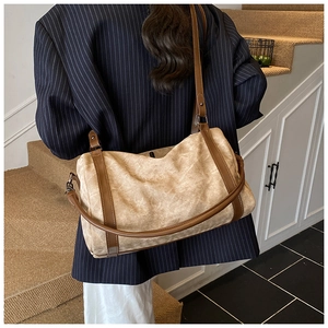 Khaki canvas crossbody bag with leather trim shown on shoulder in a lifestyle setting