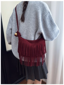 Detail of burgundy tassel crossbody bag with multi-layer fringe and wooden bead accents