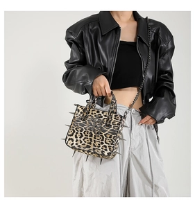 Detail of leopard print handbag with silver rivets and metal cross emblem on the front